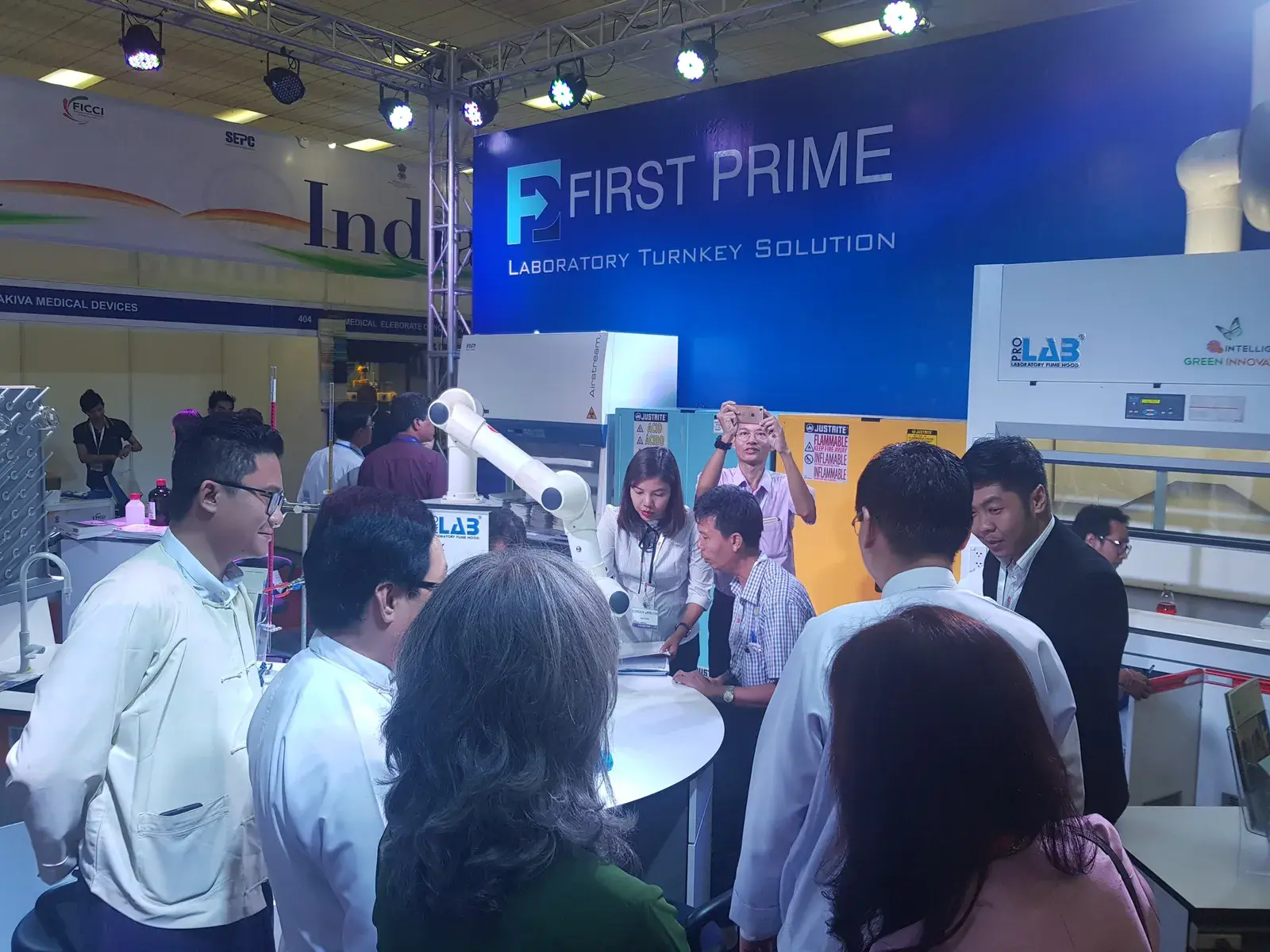 Visitors gathered around a laboratory workstation demonstration at the FIRST PRIME booth