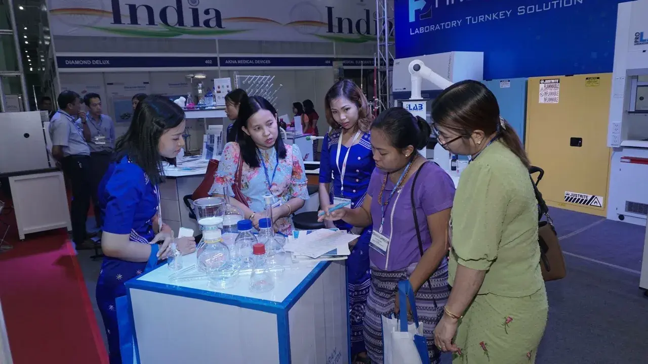 Booth staff showing laboratory glassware to visitors at the FIRST PRIME exhibition stand